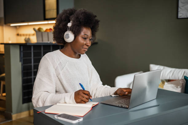 young african-american woman watching online course and writing notes - self improvement audio imagens e fotografias de stock