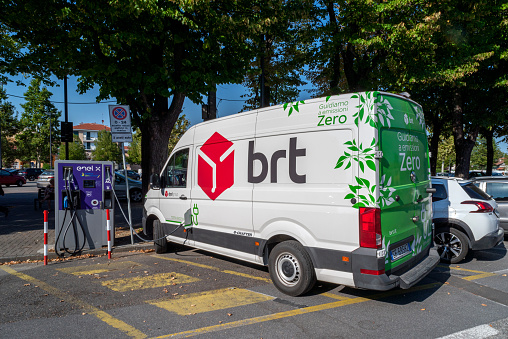 Fossano, Italy - August 25, 2022: Brt express courier electric van charging from the Enel charging column. Brt is italian Leading company for transport of company DPD of La Poste group France