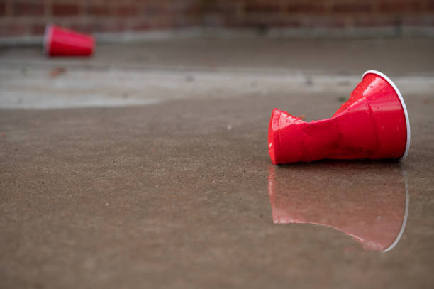 Red Plastic Disposable Cup Litter Reflected in a Puddle Red Plastic Disposable Cup Litter Reflected in a Puddle - Party Aftermath red party cup stock pictures, royalty-free photos & images
