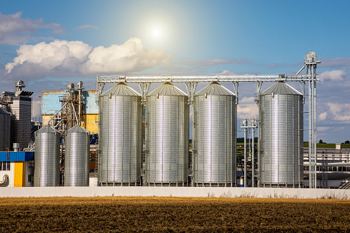 Agricultural Silos. Storage and drying of grains, wheat, corn, soy, sunflower against the blue sky with white clouds.Storage of the crop