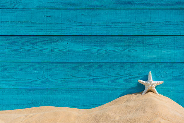 istock Turquoise colored wood grain plank wall, sand and white starfish background 1418016893