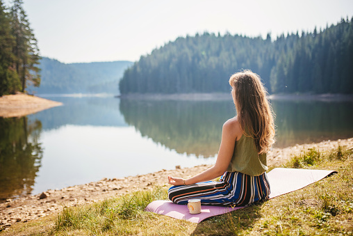 Cute female holding a mug in front of a lake