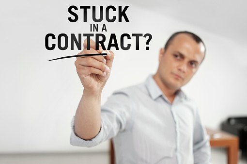Businessman writing “Stuck in a contract?” on a virtual board