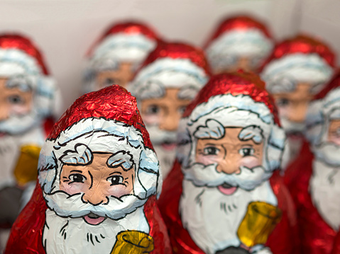 close up red and white chocholate figurine of Santa Claus with group of defocused in background