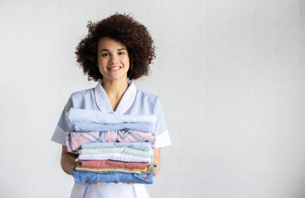 istock Happy maid doing the laundry and holding folded clothes 1418029691