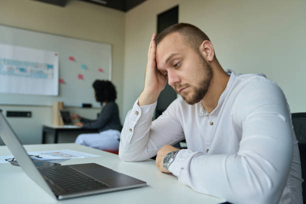 istock Tired man in a white shirt sitting at his desk 1418031273