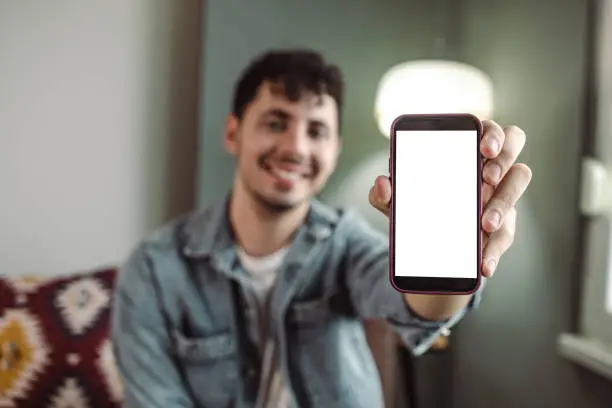 Photo of Young man holding mobile device with white screen