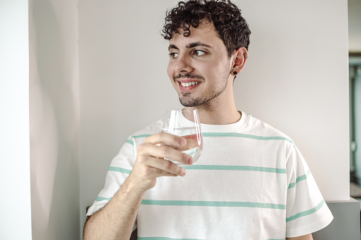 Young man holds glass of water and smiling