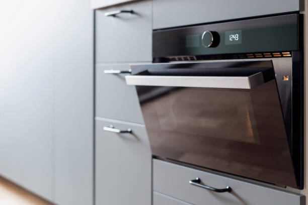 build in electric oven in contemporary kitchen closeup of electric built in oven with opened door and light inside and modern cupboard at apartment kitchen oven door stock pictures, royalty-free photos & images