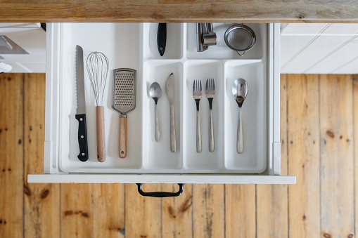 top view of opened cutlery drawer with silver ware, spoon, fork, knife and utensils at modern home kitchen, storage concept