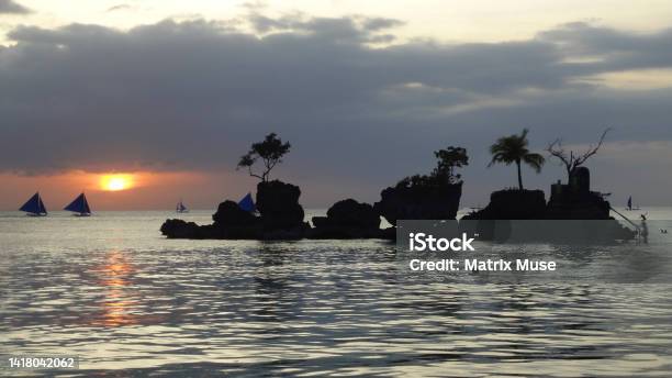 Famous Willys Rock In Boracay Paradise Island In The Evening During The Sunset With Sailing Boats On The Background And Palm Trees Growing Out Of The Rock Formation Stock Photo - Download Image Now