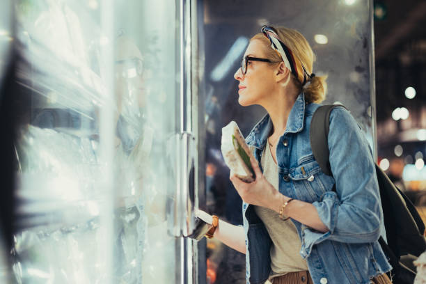 retrato de una mujer hermosa que elige productos de una nevera en el supermercado - supermarket women packaging blond hair fotografías e imágenes de stock