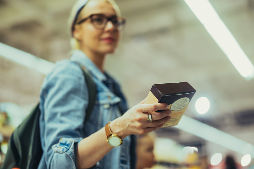 Close up shot of an unrecognizable woman holding a product box. She is wearing a watch and a ring.