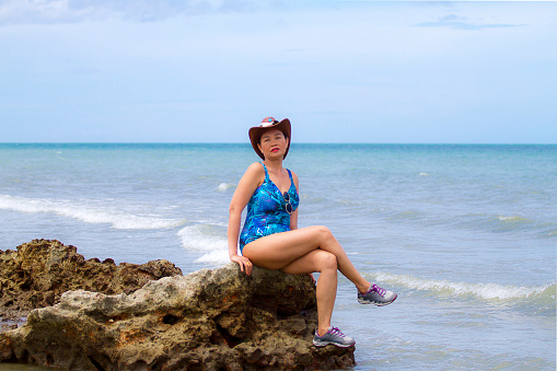 Woman with swimsuit sit relax on beach Hat Wanakon National Park, Prachuap Khiri Khan Province in Thailand is famous for travel and relax