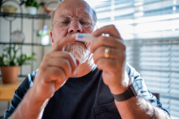 Mature Man Checking His Blood Glucose with a Home Glucometer Test Kit to Prevent of Manage Diabetes Mature Man Checking His Blood Glucose with a Home Glucometer Test Kit to Prevent of Manage Diabetes insulin stock pictures, royalty-free photos & images