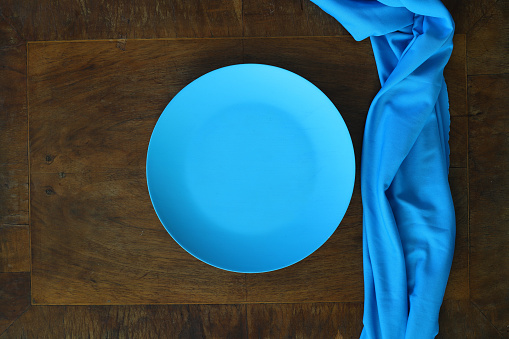 Empty blue plate on wooden table. Food background for menu. Flatlay, top view.