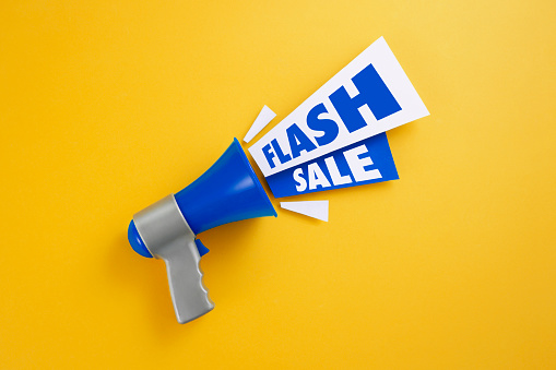 Blue megaphone with colored papers and flash sale text on yellow background