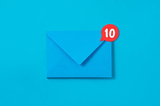 Blue envelope with message symbol attached on it on blue background