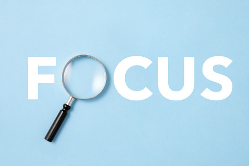 Focus word created with magnifying glass on blue background