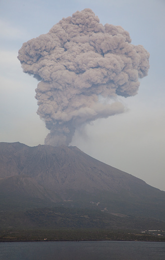 Sakurajima is an active stratovolcano, formerly an island and now a peninsula, in Kagoshima Prefecture in Kyushu, Japan. Seen here erupting a huge cloud of smoke and ash.