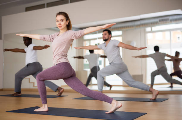 istock Woman and men practising warrior II pose 1418057590