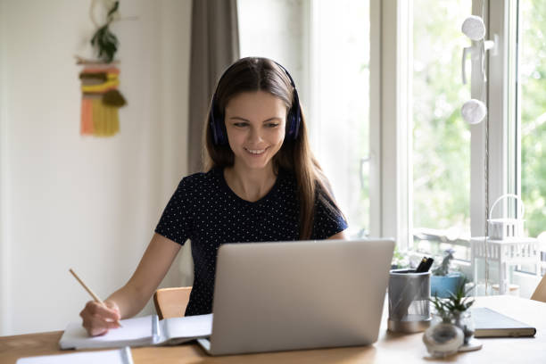istock Happy engaged young female student in wireless headphones watching webinar 1418063629