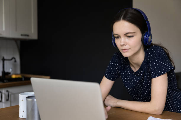 istock Serious millennial student girl in wireless headphones using laptop 1418063654