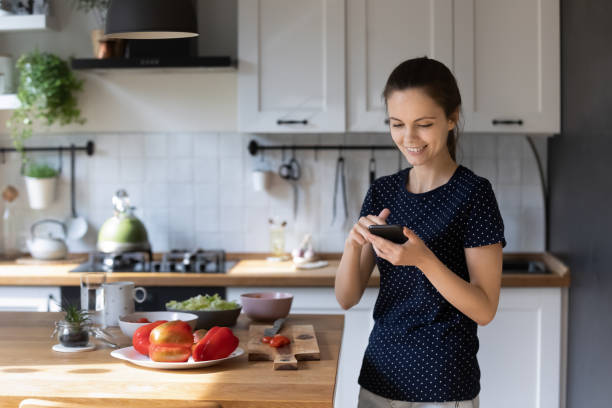 istock Cheerful chef blogger woman using mobile phone at kitchen table 1418063735