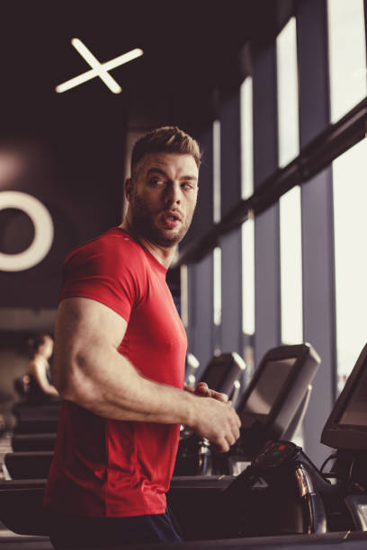 istock Attractive male athlete looking away while running on a treadmill 1418064363