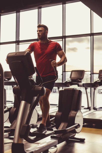 istock Male athlete using elliptical machine at the gym 1418064364