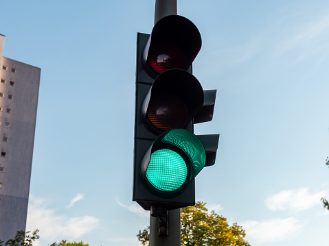 Green shining traffic light for car drivers. This light signal next to the street shows that the traffic can move on. Safety on German streets is generated. Road traffic regulations and laws in Europe