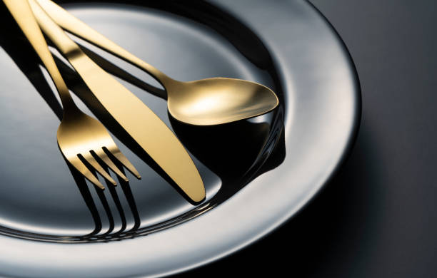istock Gold knives, forks and spoons on black plates. 1418072367