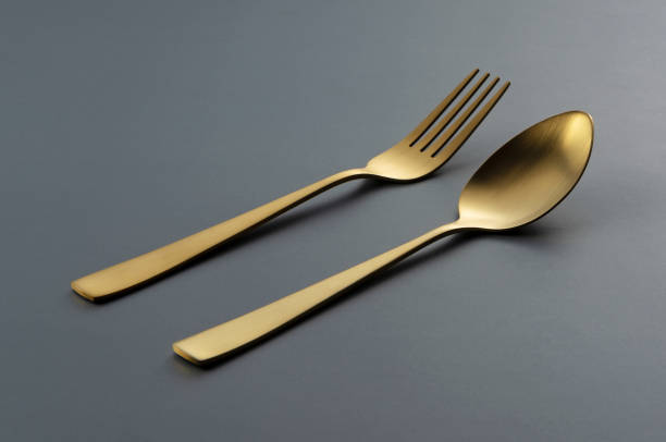 istock Gold knives and spoons set against a black background. 1418072382