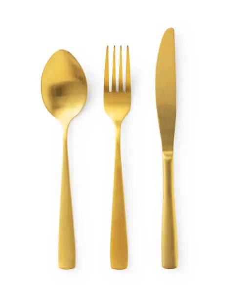 Gold knives, forks and spoons placed on a white background. Beautiful gold cutlery. View from above.