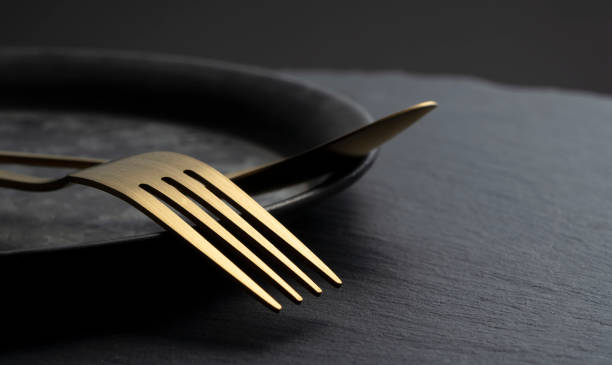 istock Gold fork and spoon placed on a black iron plate. 1418072465