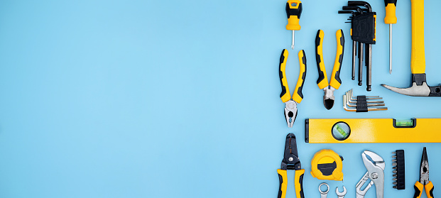 different type of yellow and black hand tools flat lay isolated baby blue background with copy space