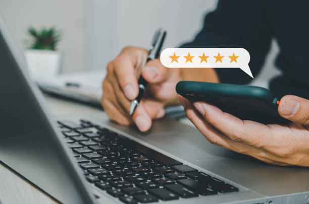 istock hand businessman holding smartphone and use computer laptop. Customer service feedback 5 star review satisfaction positive business concept. 1418075744