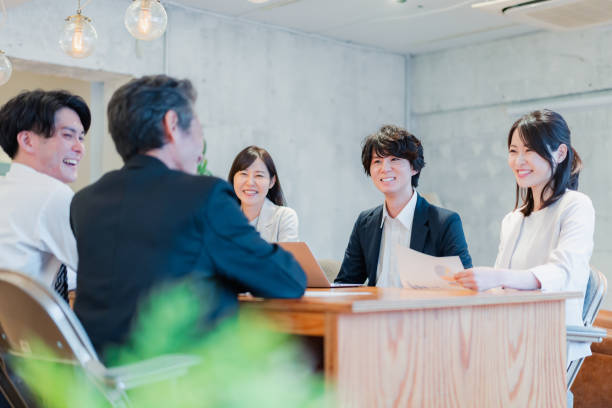 homme d’affaires en réunion avec le sourire - laptop japanese ethnicity businessman desk photos et images de collection