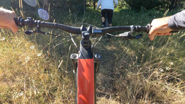 istock POV as mountain biker follows friend down grassy trail 1418081678