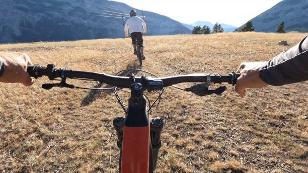 istock POV as mountain biker follows friend down trail 1418081769