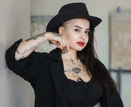 Portrait of a stylish young woman with tattoos, looking at camera