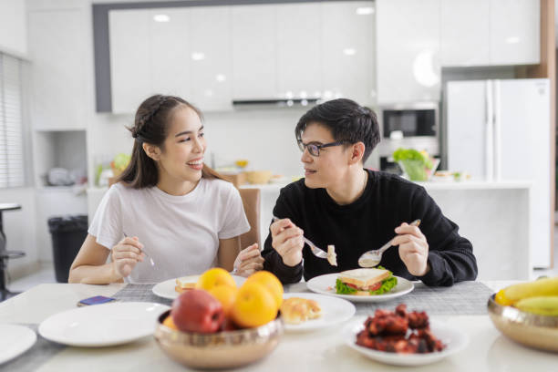istock Asian Couple Having Breakfast Sitting In Kitchen 1418087086