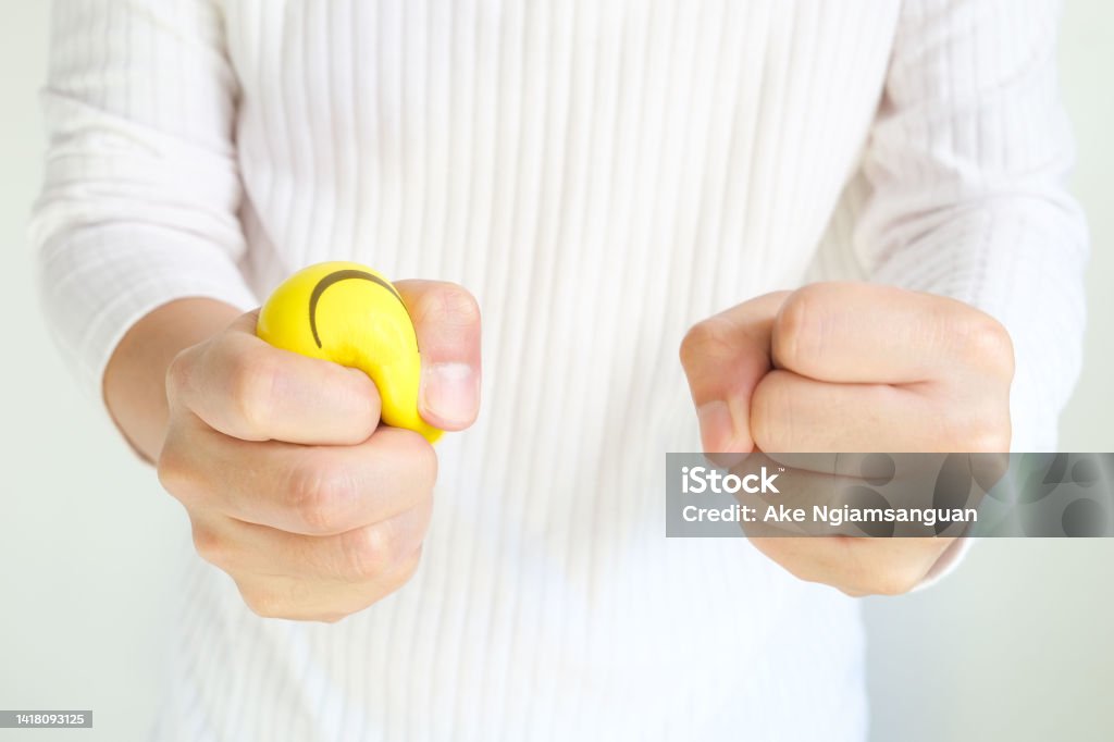 Hands of man with a gentle personality He exhibits stressful behavior from work, and he squeezes the yellow ball expressing emotion, anger, displeasure. Medical concepts and emotional regulation Adult Stock Photo