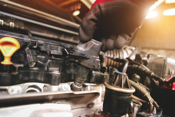 istock A auto mechanic is installing  ignition coil for a spark plug into the ignition socket of the engine block 1418099966