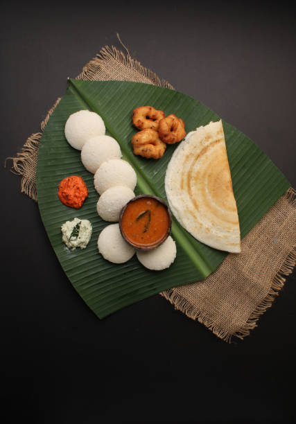 gruppo di cibo dell'india meridionale come masala dosa, idli, wada o vada, sambar, servito su foglia di banana con chutney di cocco colorati - dosa foto e immagini stock