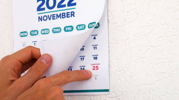 A man flips through the November page 2022 and points a finger at Christmas date on the next one