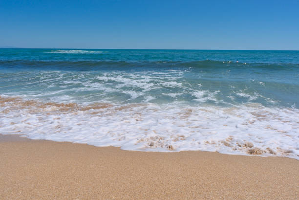 istock Clear emerald green sea with white foam and clean sandy beach 1418106349