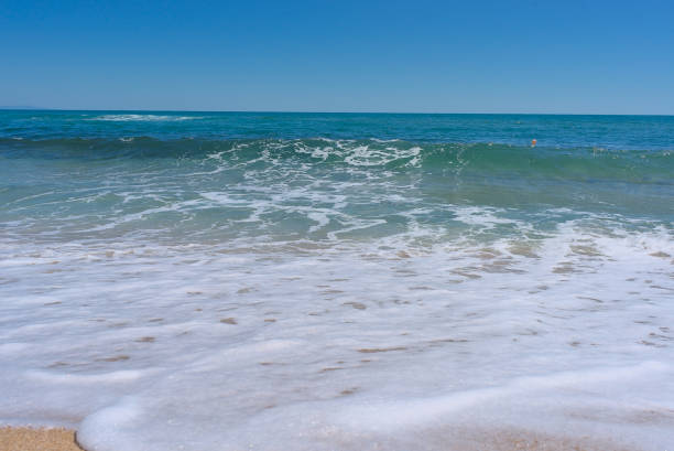 istock Clear emerald green sea with white foam and clean sandy beach 1418106454
