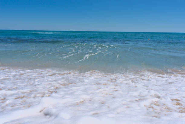 istock Clear emerald green sea with white foam and clean sandy beach 1418106499