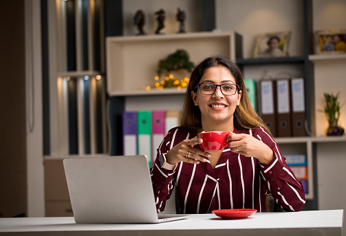 Businesswoman using laptop and drinking coffee at home
